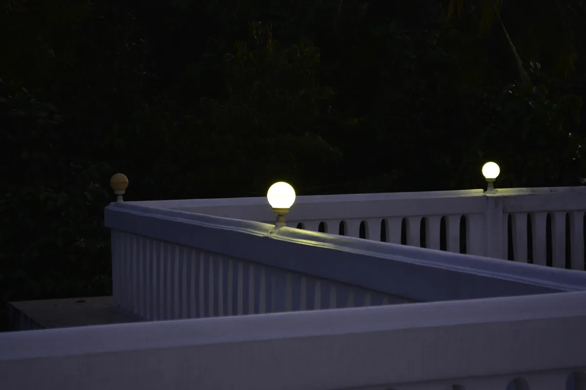 Deck railing at night with glowing round post lights illuminating the dark surroundings.