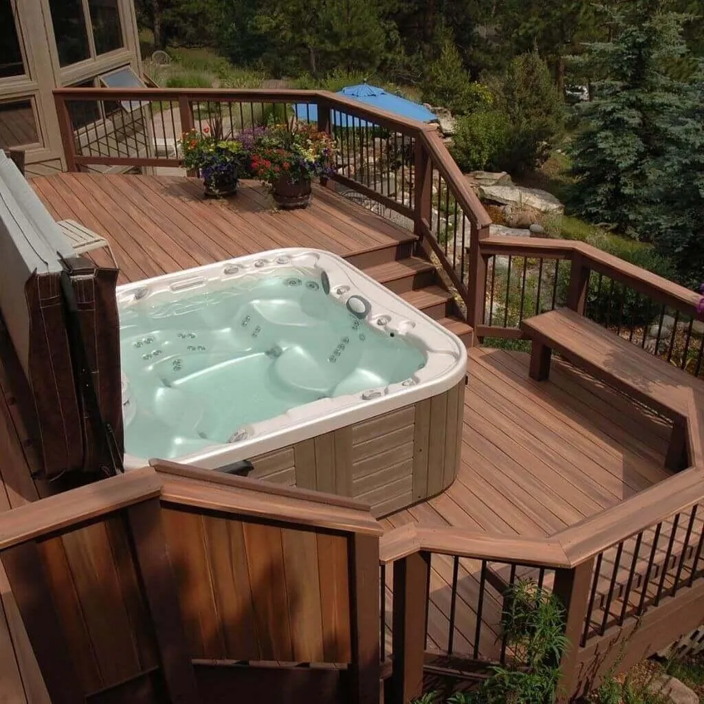 Multi-level wooden deck with built-in seating and a hot tub, decorated with potted plants and overlooking a landscaped yard.