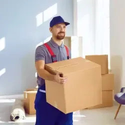 Pracovník společnosti STĚHUJEME PRAHU nese velkou krabici během stěhování.