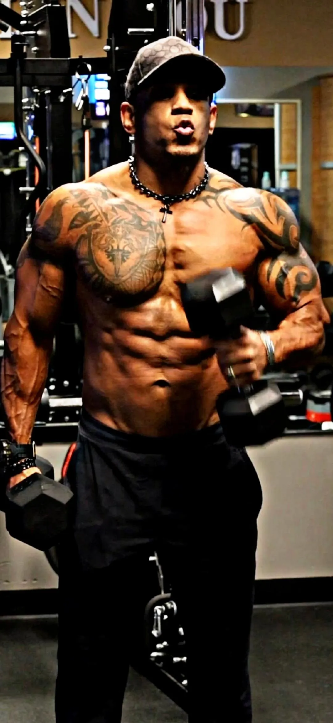 a man standing in a gym looking at his reflection in the mirror