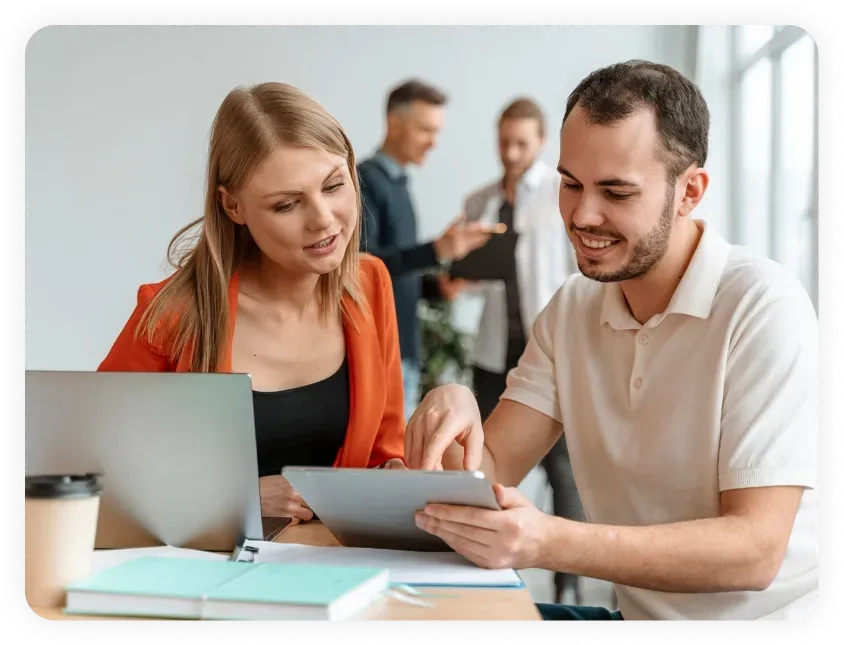 Two colleagues collaborating on a tablet in a modern office environment, symbolizing teamwork and strategy for effective Dallas SEO services and local SEO campaigns.