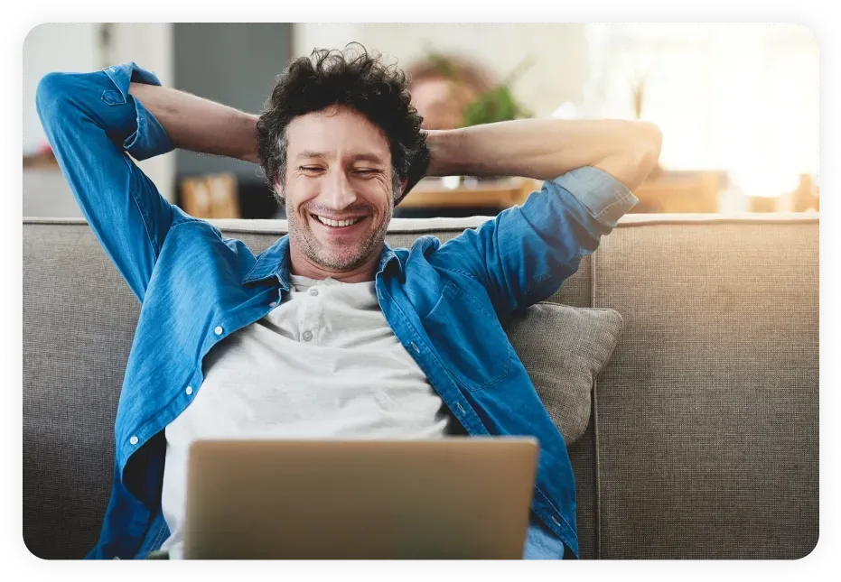 Smiling professional relaxing on a couch with a laptop, reflecting the ease and confidence gained through optimized local SEO in Dallas.