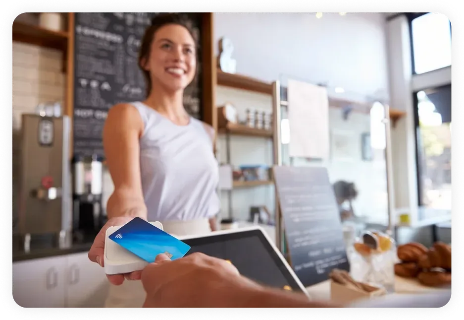 Friendly cashier accepting a contactless payment at a café, representing the business growth achieved with Dallas SEO services driving local customer engagement.