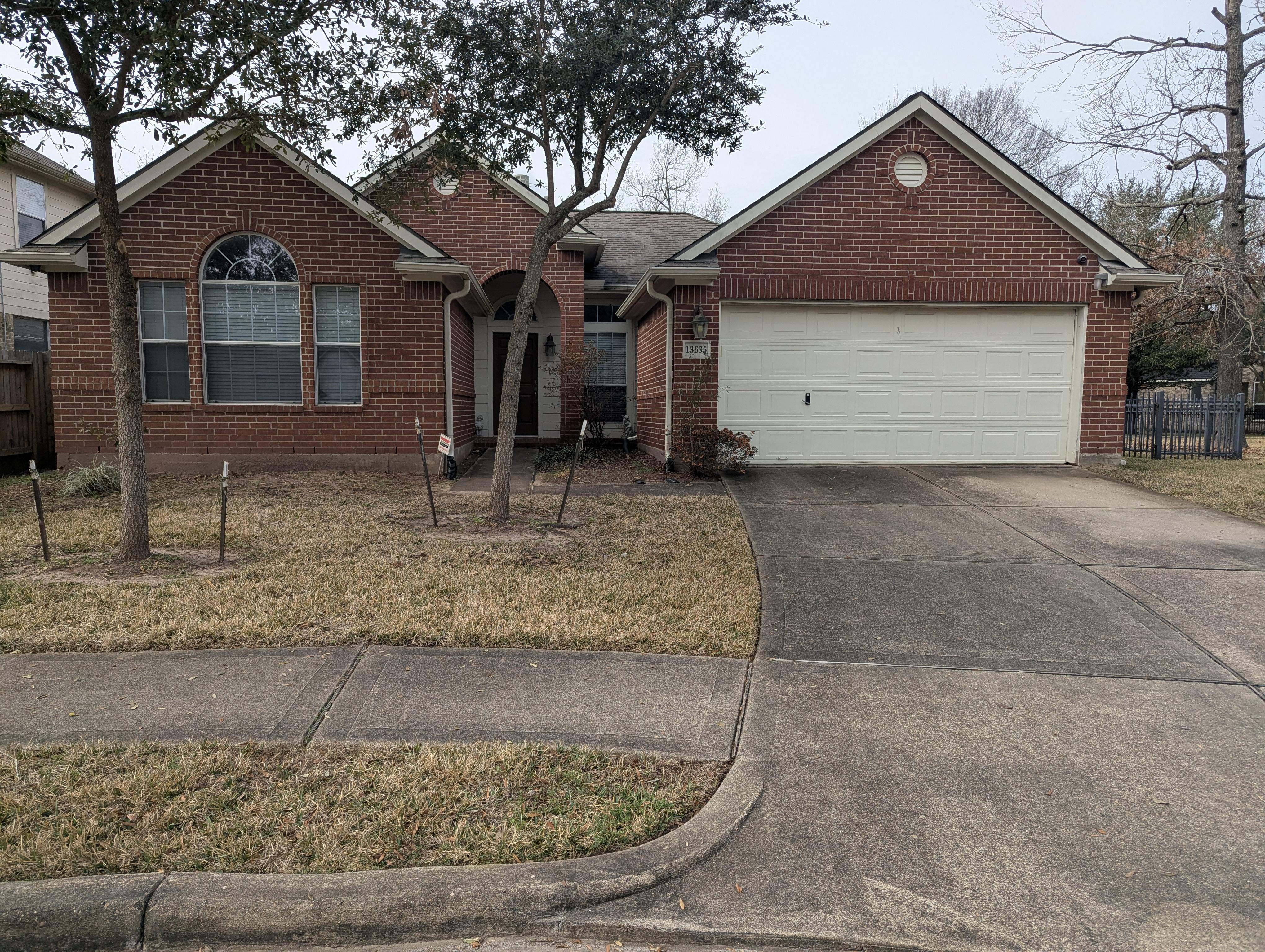 Dirty brick home and concrete driveway before pressure washing in Houston TX with algae, mildew, and surface staining
