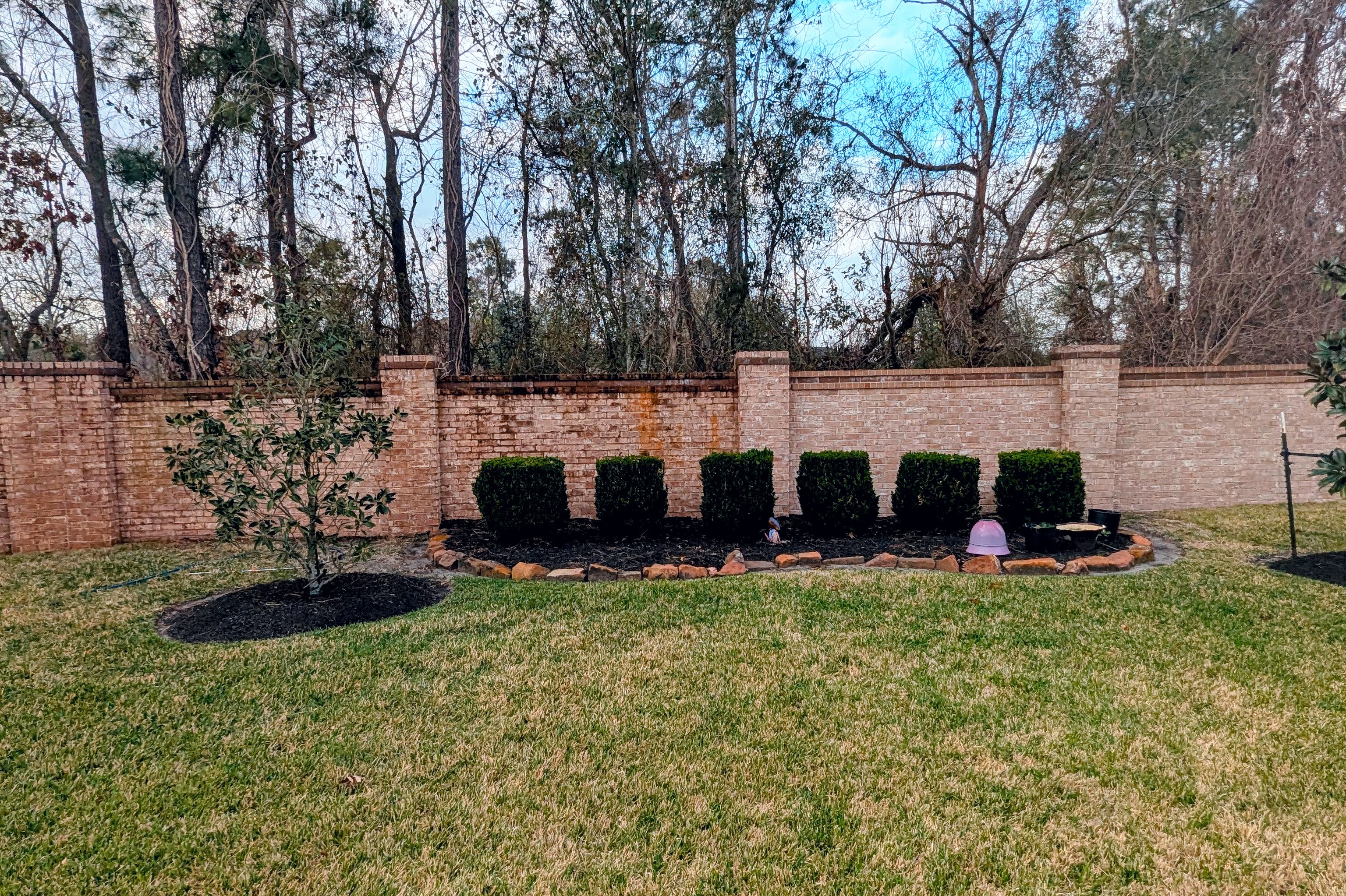 Commercial property pressure washing in Houston TX cleaning brick wall landscaping area for business property