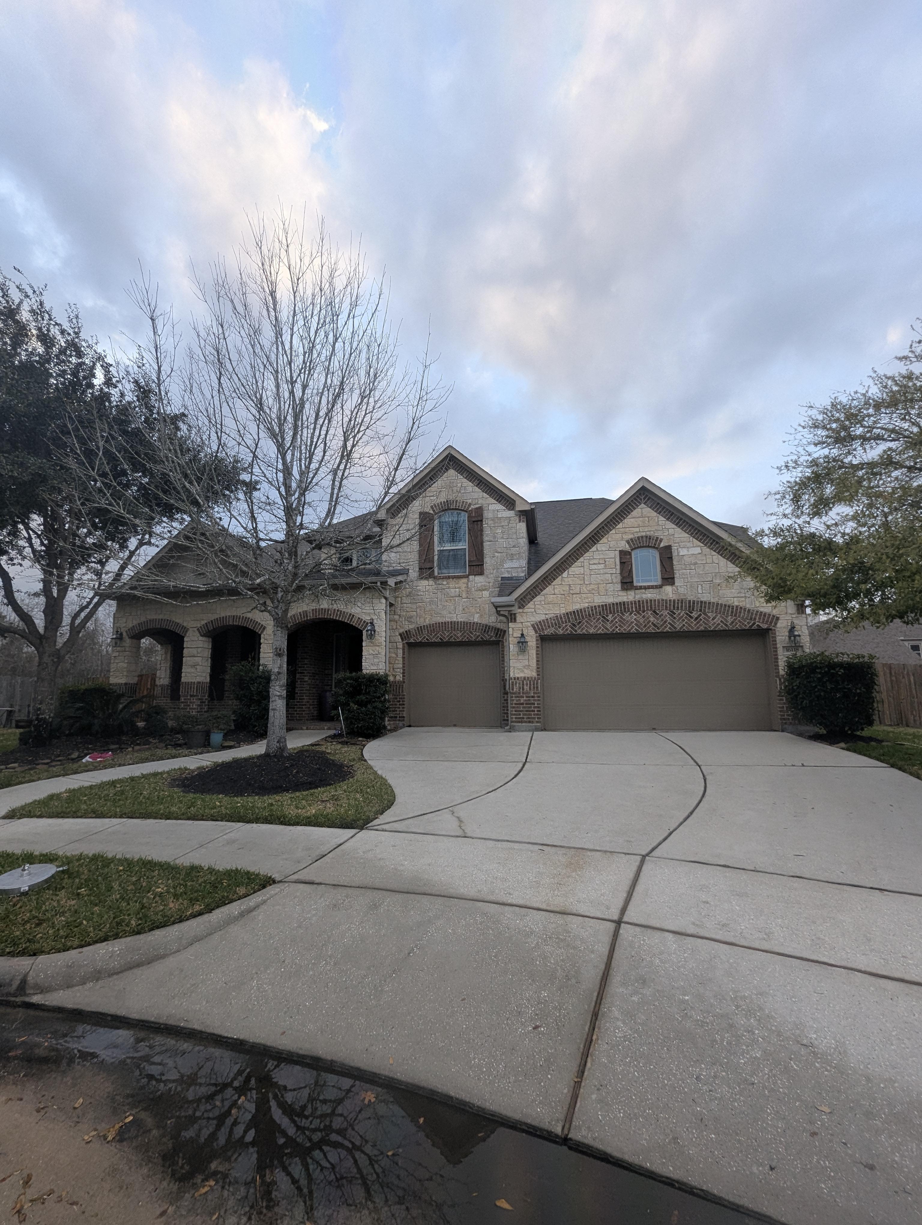 Large residential home with curved driveway after professional pressure washing in Houston TX showing bright clean concrete and restored exterior surfaces