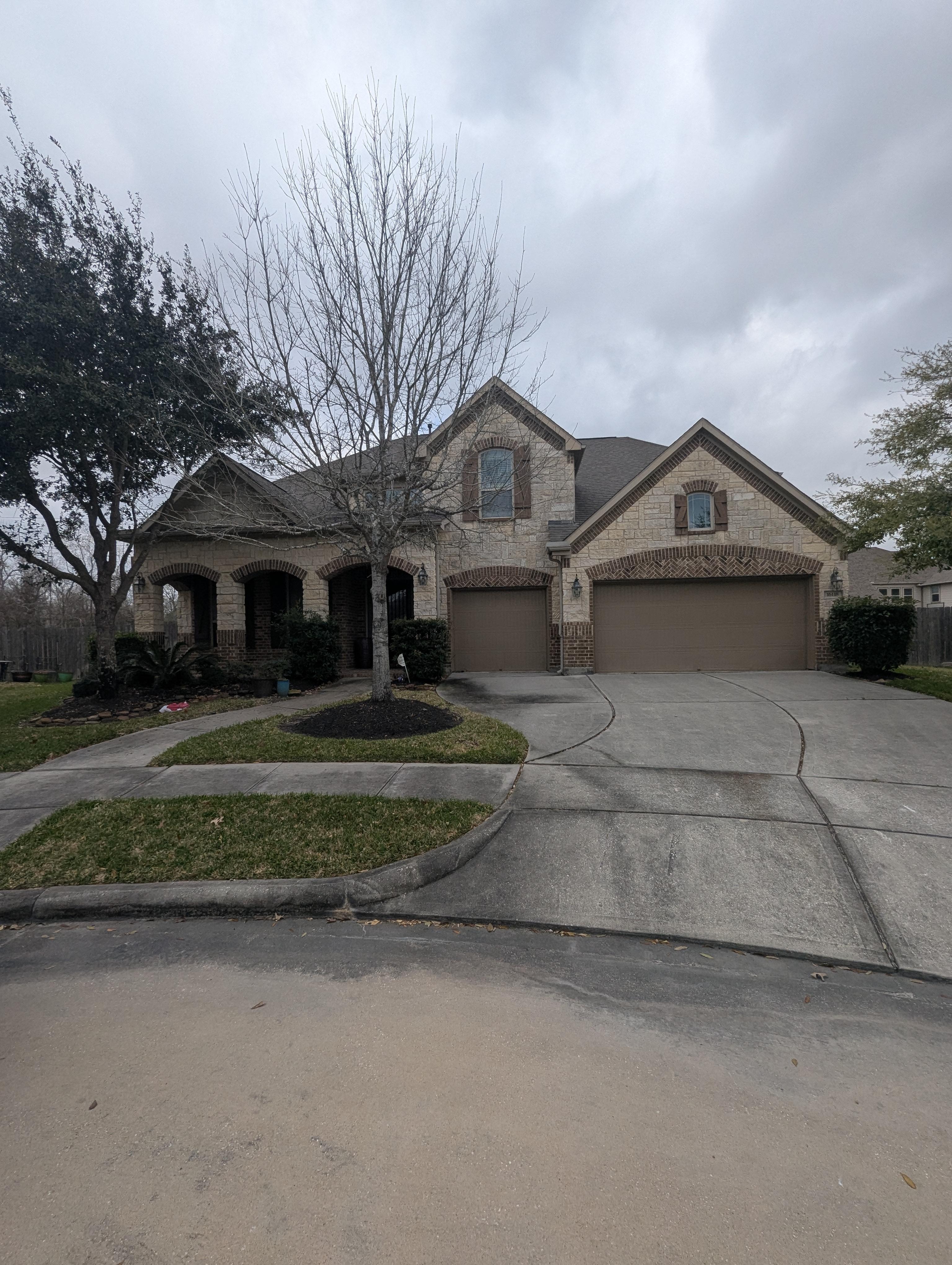 Residential driveway and home exterior before pressure washing in Houston TX with dirt, algae, and surface buildup on concrete and siding