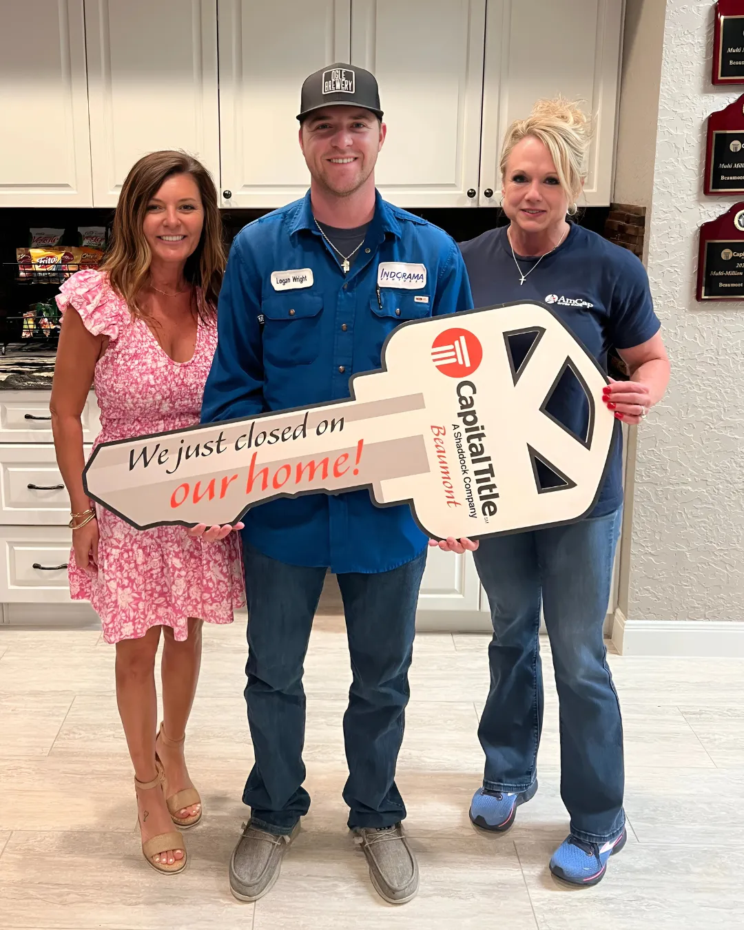 Couple celebrating home closing day, holding a "Closing Day" sign with "Great American" branding, in a welcoming office setting.