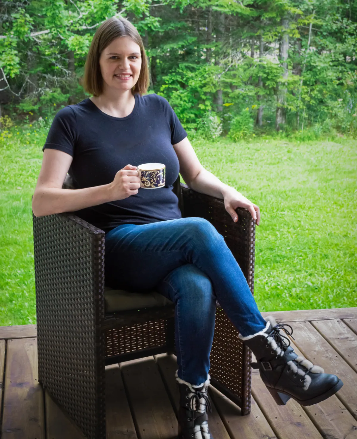 young woman with short dark hair sitting outside with a mug