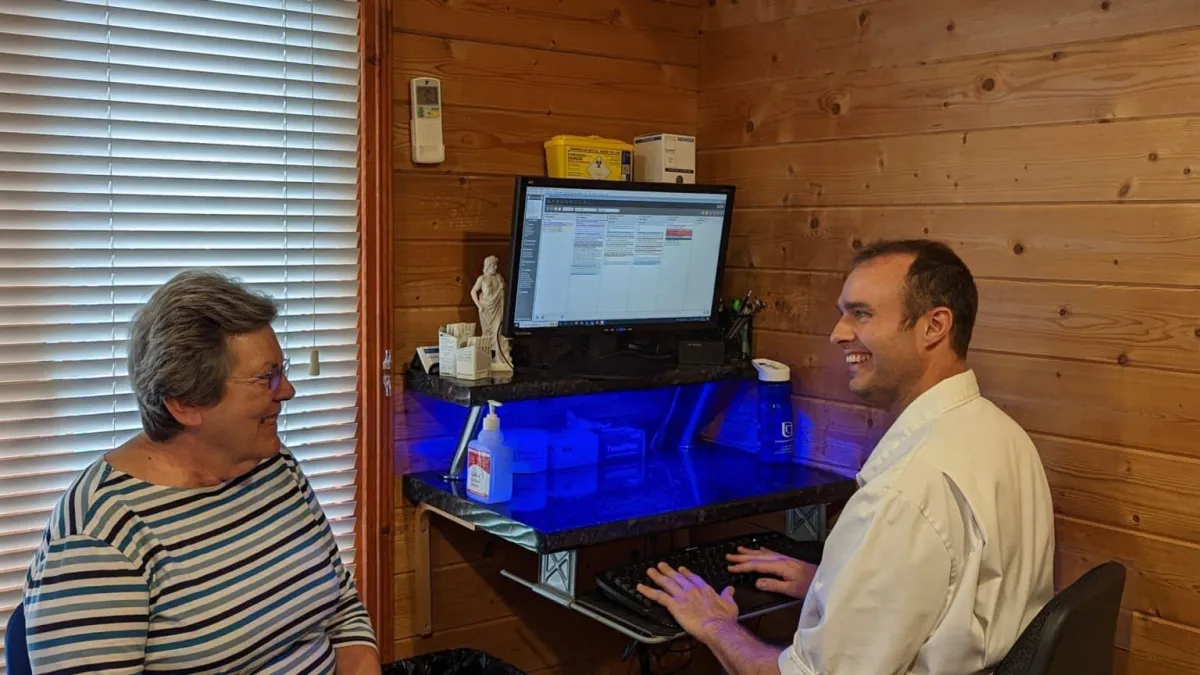 Clinician reviewing a digital assessment report on a tablet with a patient in a modern clinic.