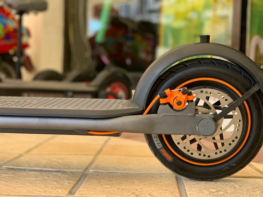 girl in pink dress riding red and black kick scooter during daytime