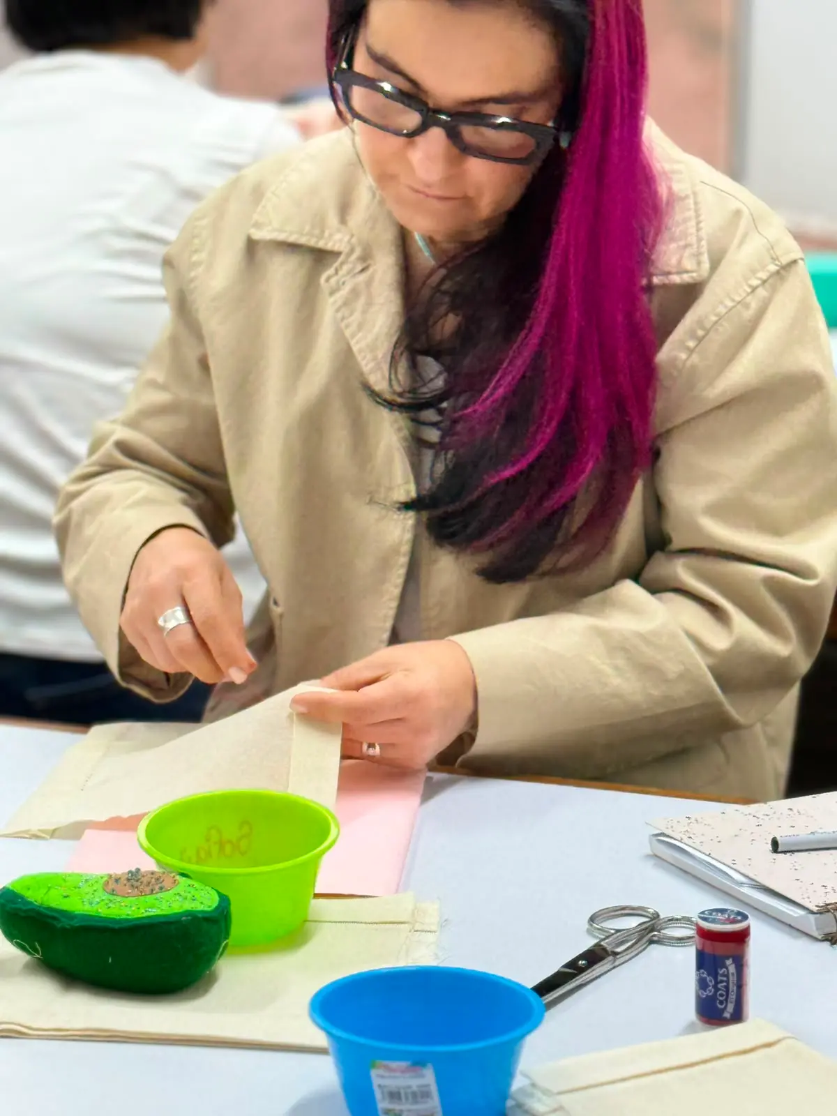 Estudiante realizando acabados de costura a mano en tela durante una clase presencial en el taller de Sistema CyC