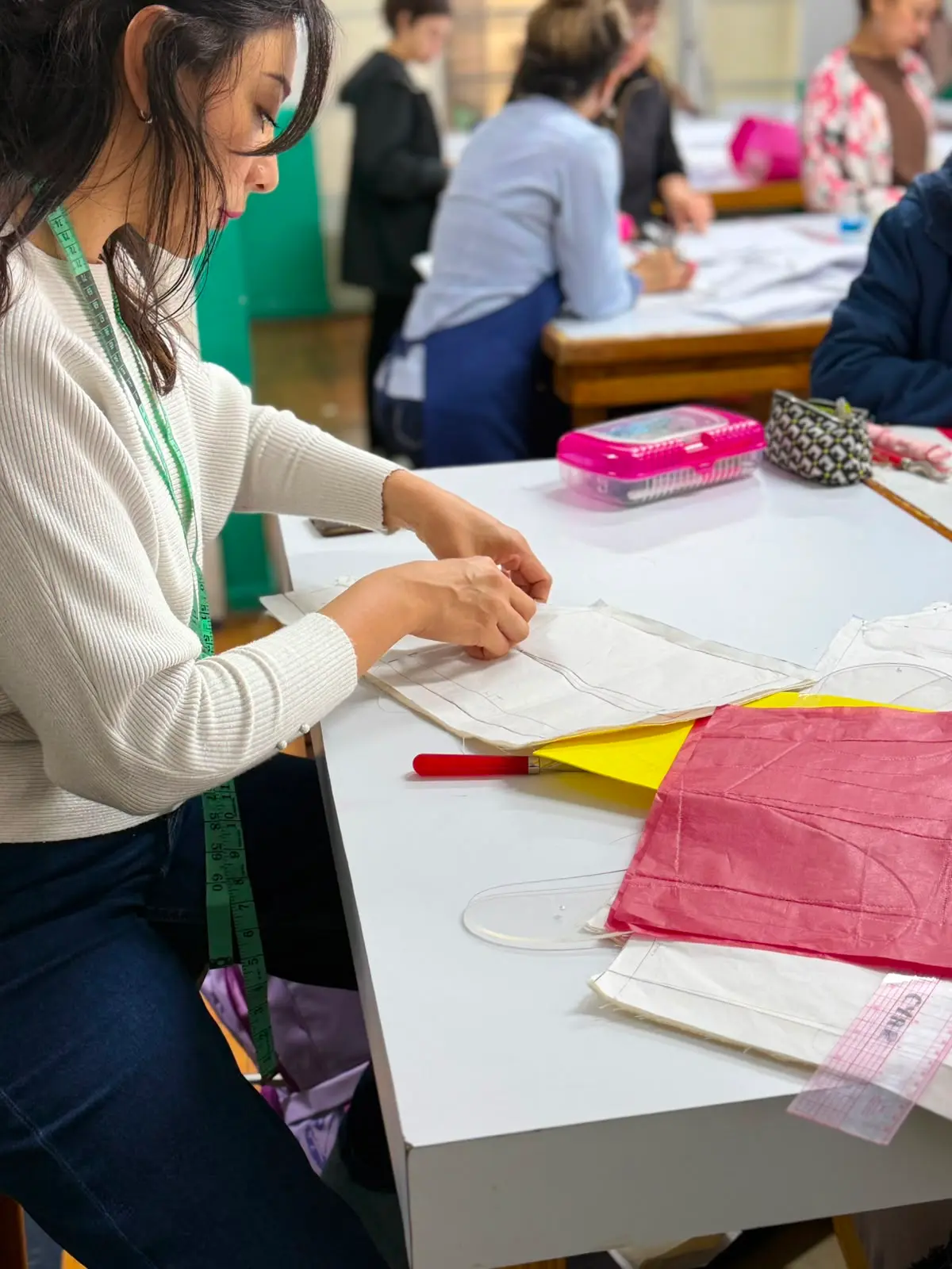 Alumna de Sistema CyC realizando el trazo y ajuste de patrones de papel sobre mesa de trabajo durante clase de patronaje