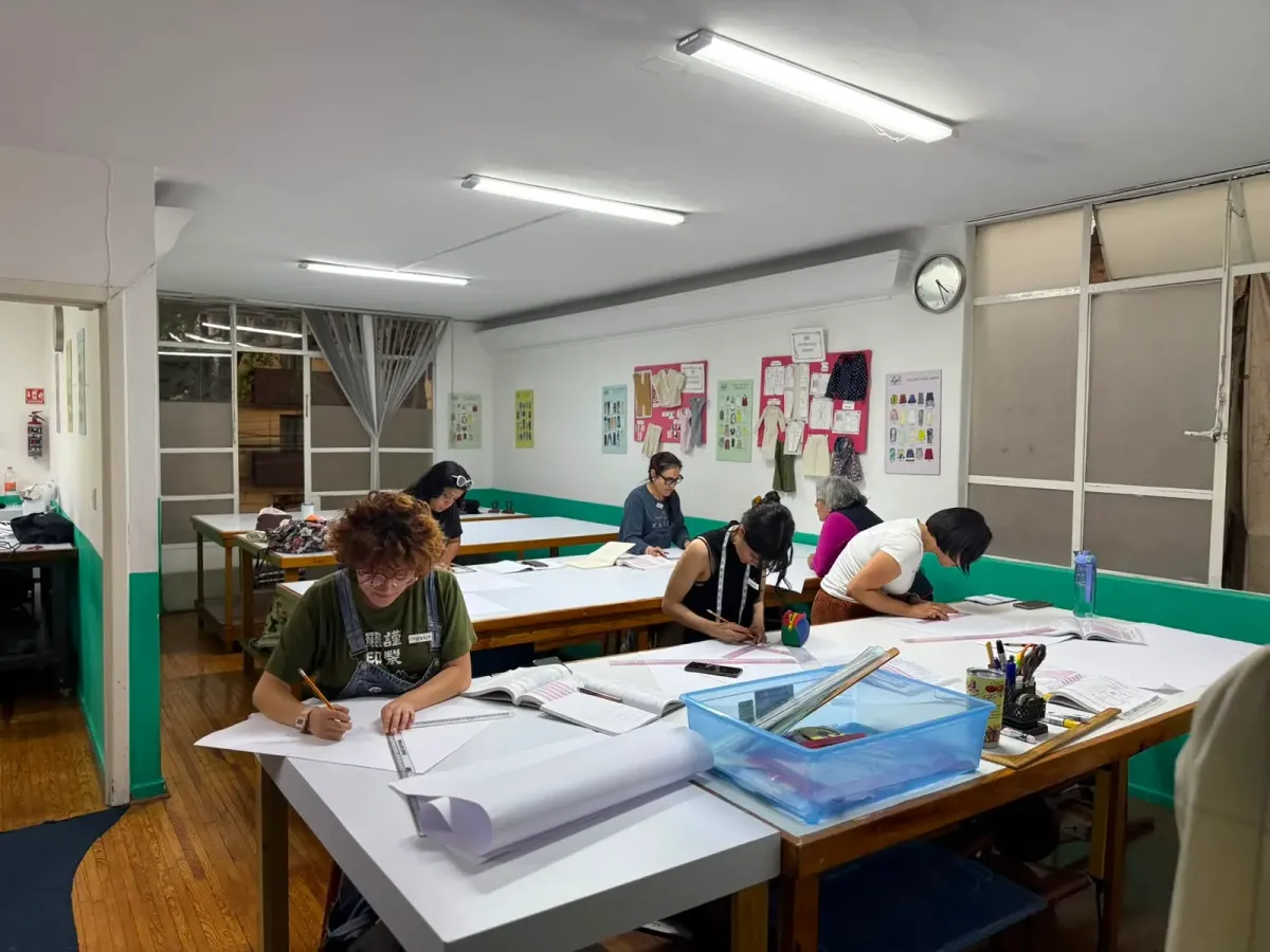 Alumnas trabajando en mesas de trazo durante una clase presencial de patronaje en el taller de Sistema CyC.