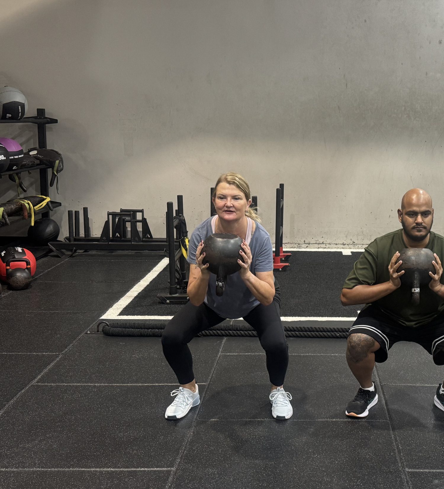 Sempre Strength Club members squatting with kettlebells at Goodlife Burleigh