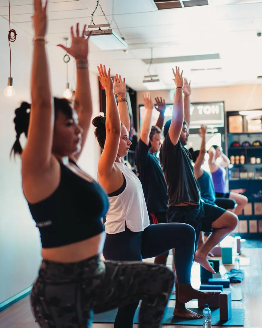 Group of students practising a standing yoga pose at One Big Heart, building strength, balance and focus.
