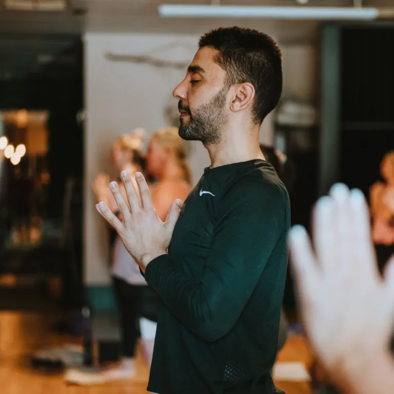 Person standing on a yoga mat with grounded feet in a calm studio setting