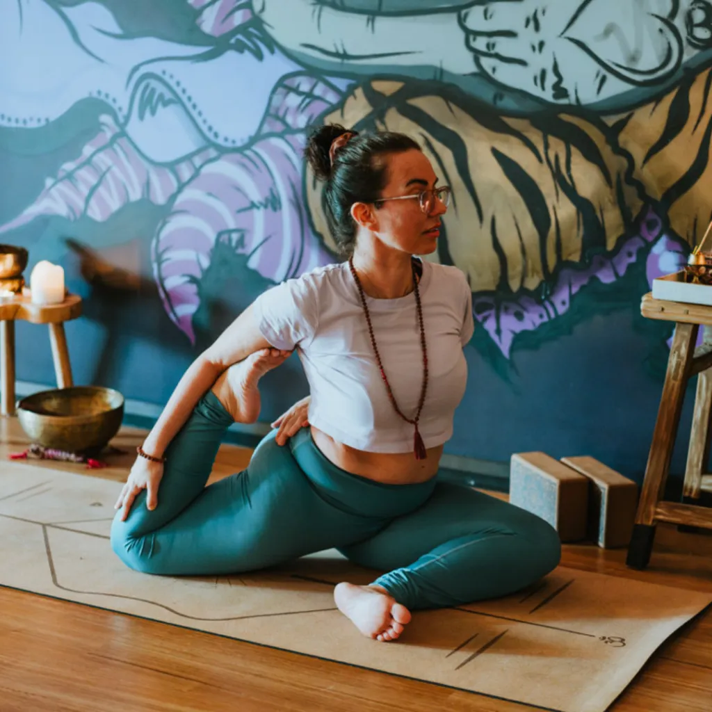 Student in Reclined Pigeon pose for sciatica relief at One Big Heart yoga studio