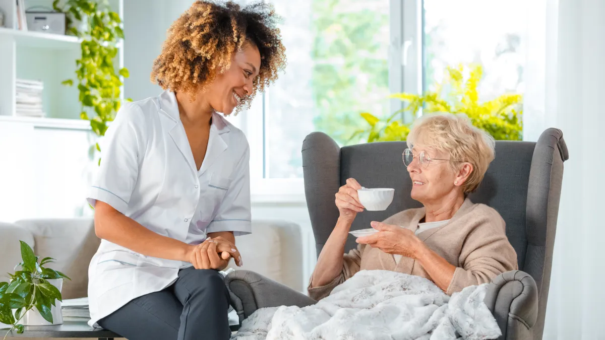 Carer and elderly patient hugging 