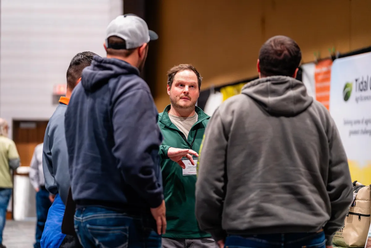 Group of attendees networking near an exhibit booth at the Eco-Ag Conference & Trade Show