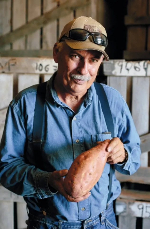 Rod Ardoin of Acadian Family Farm holding organic sweet potato in Caddo County, Oklahoma – certified organic vegetable farmer specializing in Traditional Orange, Japanese Murasaki, and Red Gourmet sweet potatoes