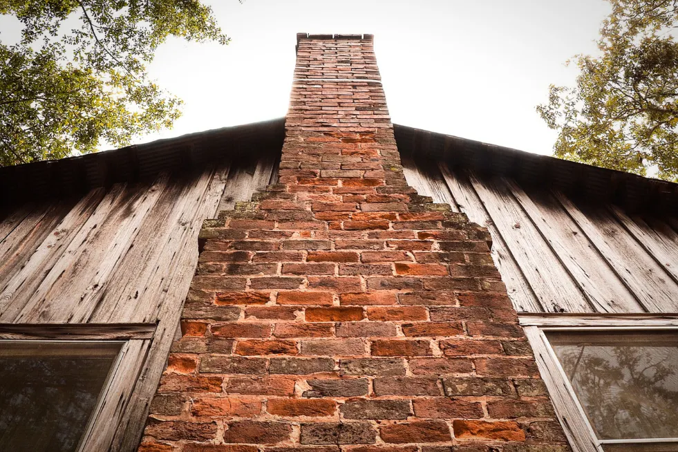 Brick fireplace and chimney from the outside of a home.