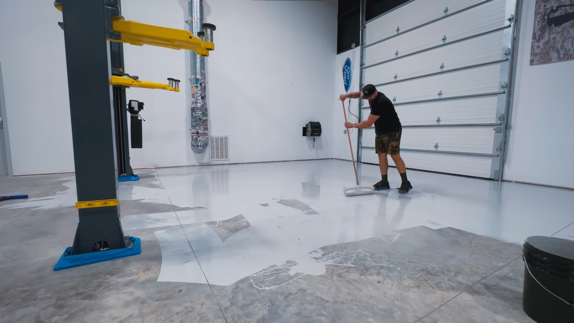 black tshirt man uses brush mop for white epoxy on floor