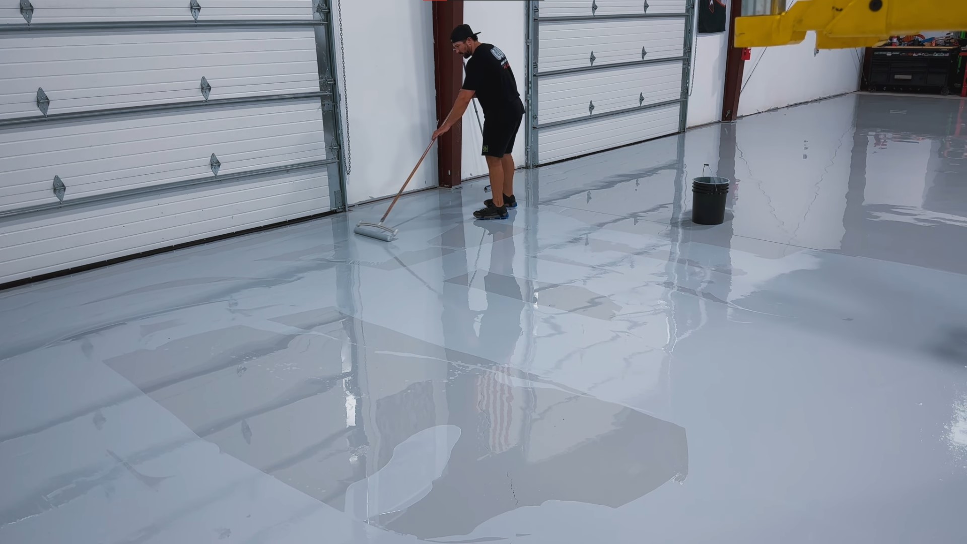 using paint roller to roll second epoxy coat over warehouse floor