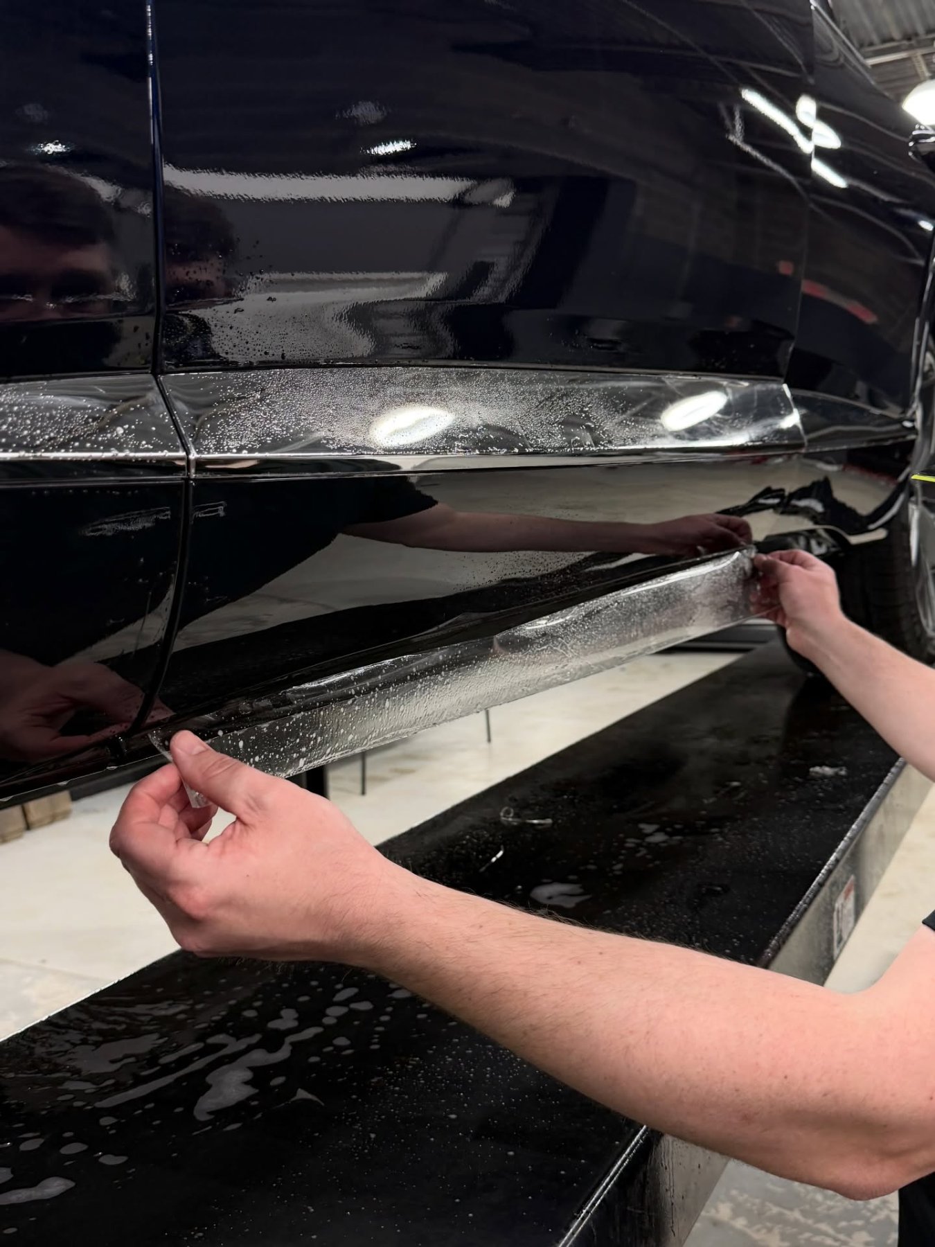 PWP Detailing installer wrapping paint protection film along a rocker panel