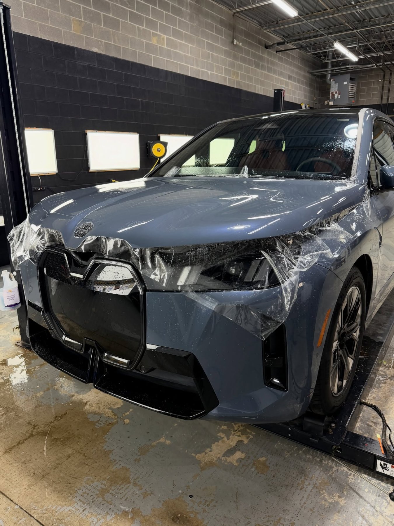 BMW iX covered in paint protection film mid-install at PWP Detailing