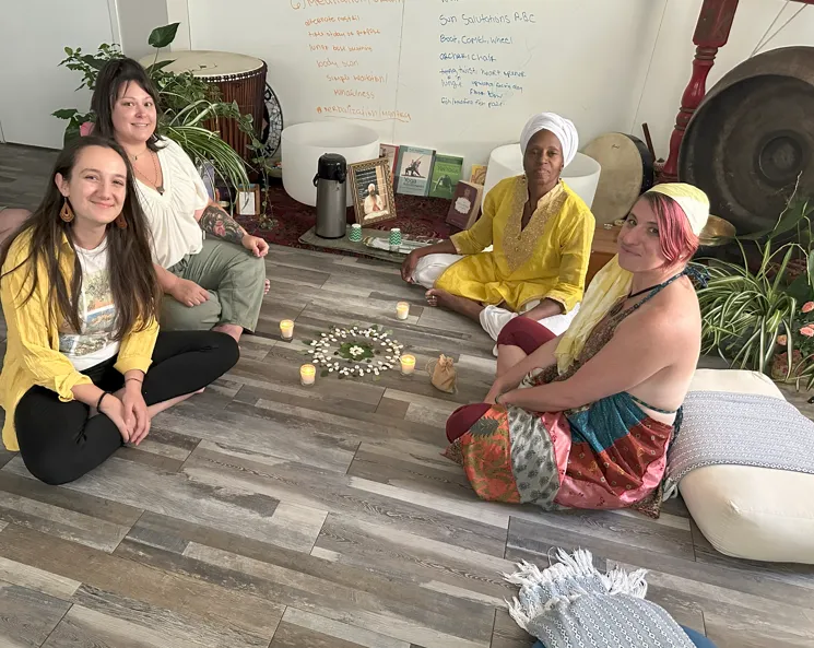 Group of yoga graduates sitting around a nature mandala