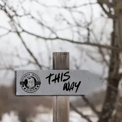 Wayfinder sign on a wood post in front of trees