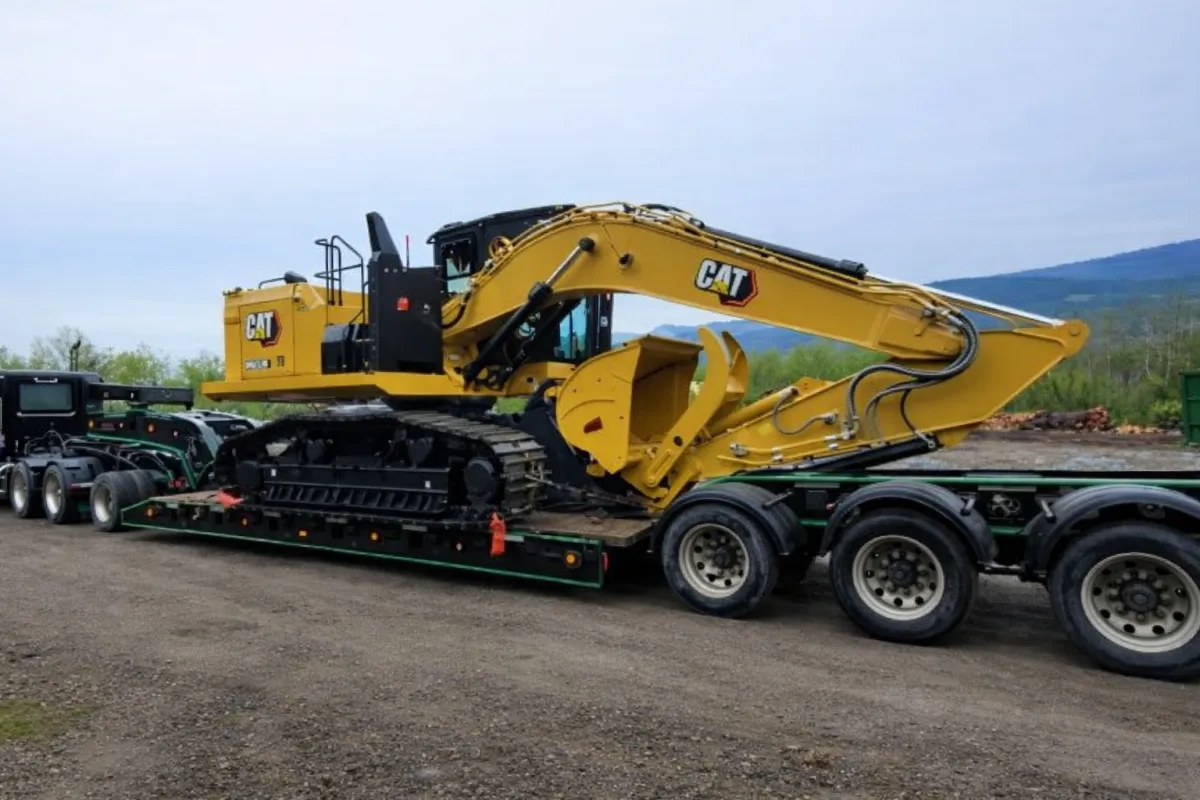 CAT excavator loaded on tri-axle trailer for professional equipment transport and delivery across Western Canada