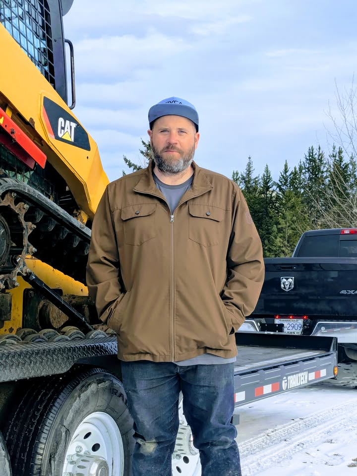Colin McInnis, founder and equipment expert at McInnis Industries, standing in front of CAT skid steer loader