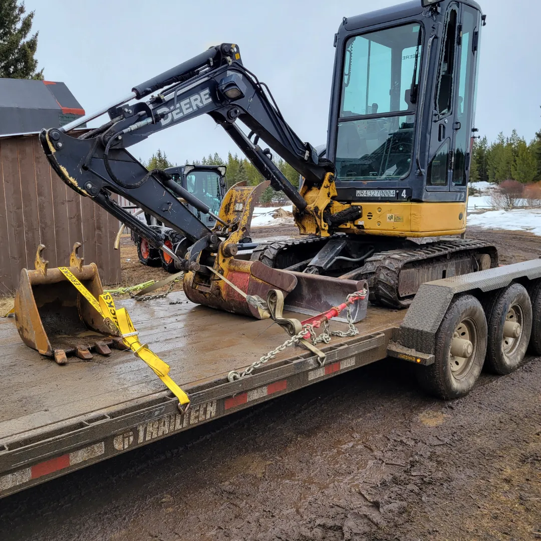 John Deere excavator with various attachments and equipment on tri-axle trailers -McInnis Industries Contractor Services