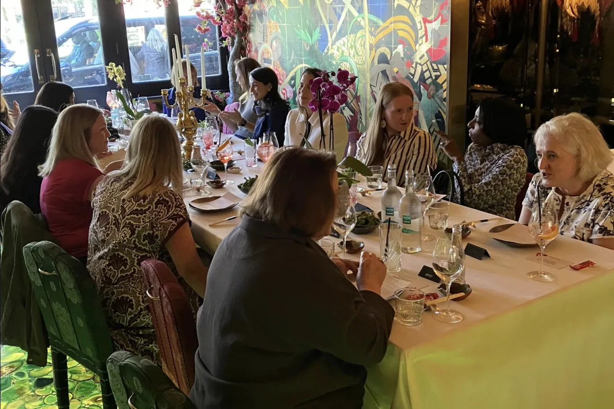 An image of Angela Tella, Executive Coach seated confidently at a beautifully set table in an elegant, intimate setting, with other female founders and leaders.