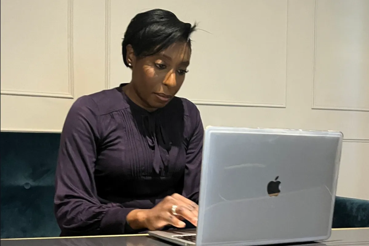 An elegant image of Angela Tella seated at a desk working on laptop