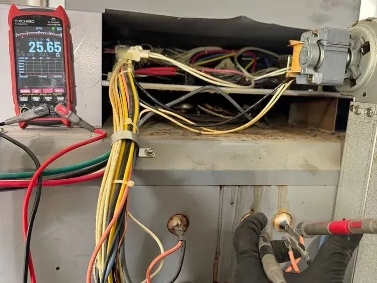 Technician performing electrical diagnostics on oven heating circuit using a digital multimeter