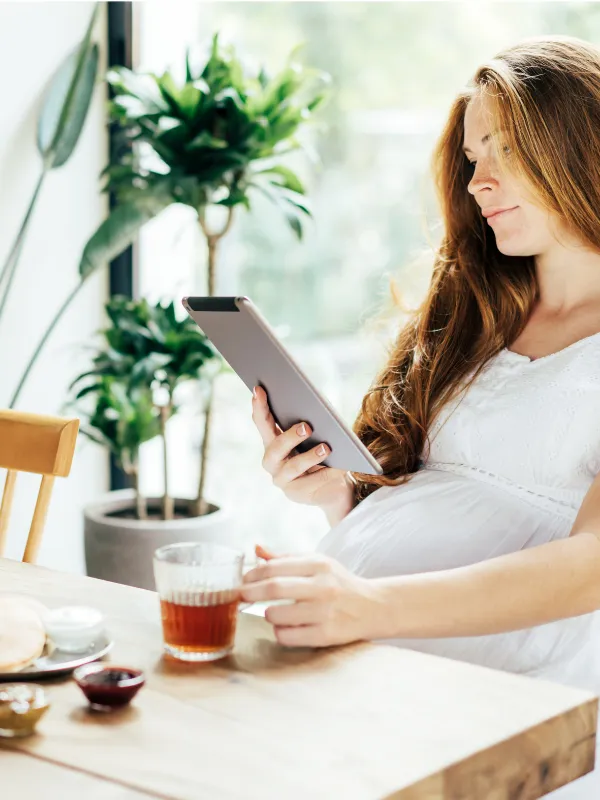 An expecting mother relaxes and looks at her iPad.