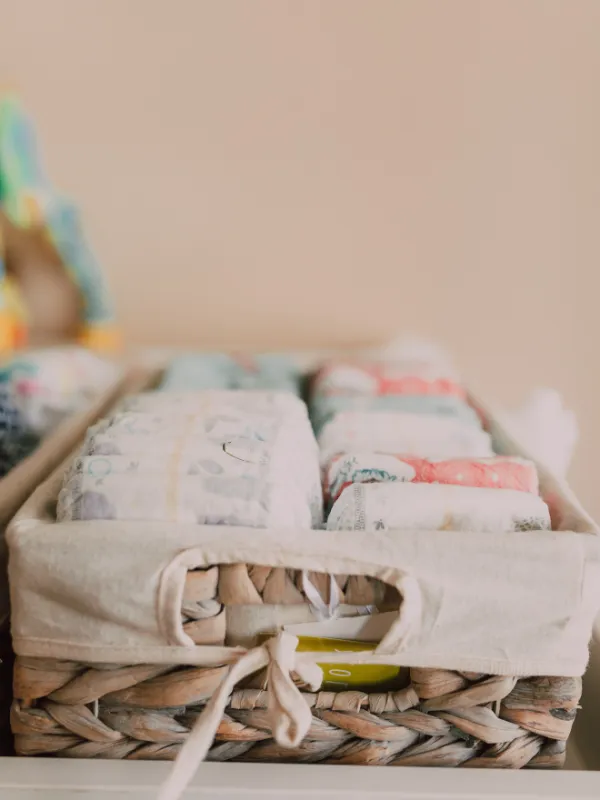 A basket with diapers and burp rags.