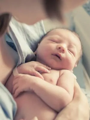 A swaddled newborn baby yawns.