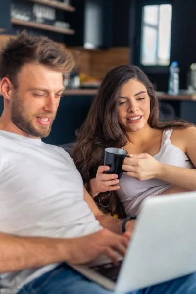 An expecting couple look at their laptop.