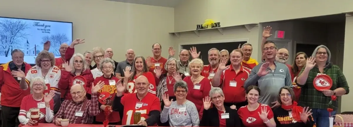 large group of people in KC Chiefs shirts waving