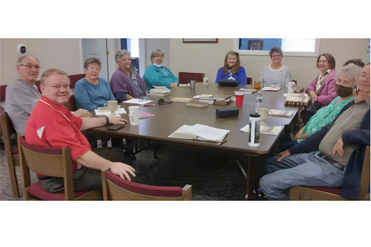 group of men and women around a table with bibles