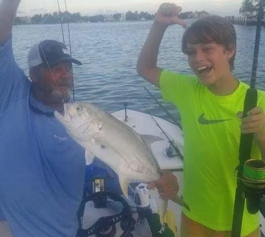 Father and son on a boat in Folly Beach, SC holding a fishing rod and their catch together