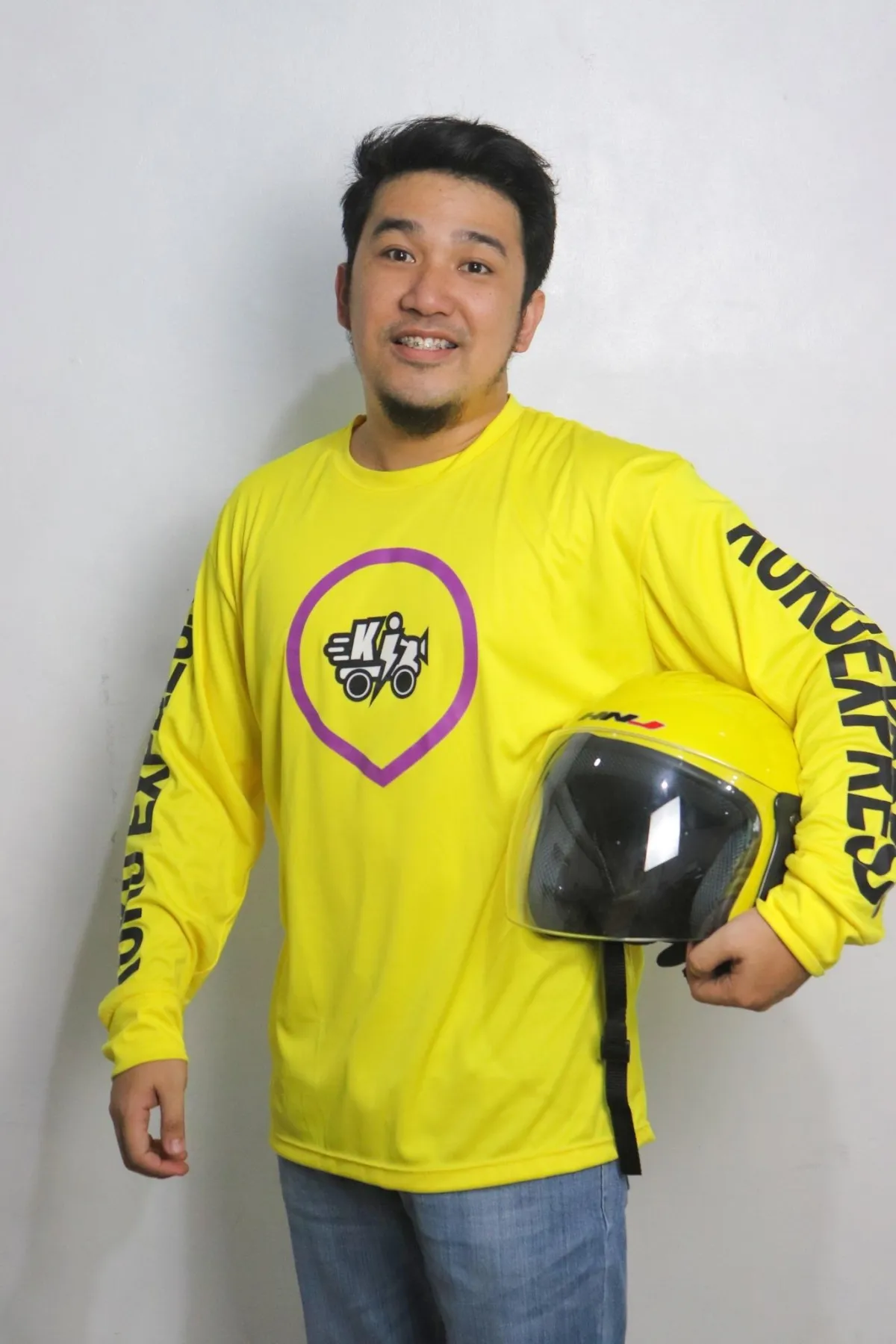 Photo of Chicoi Gonzales wearing his kuku express uniform and holding a yellow helmet on his left arm.