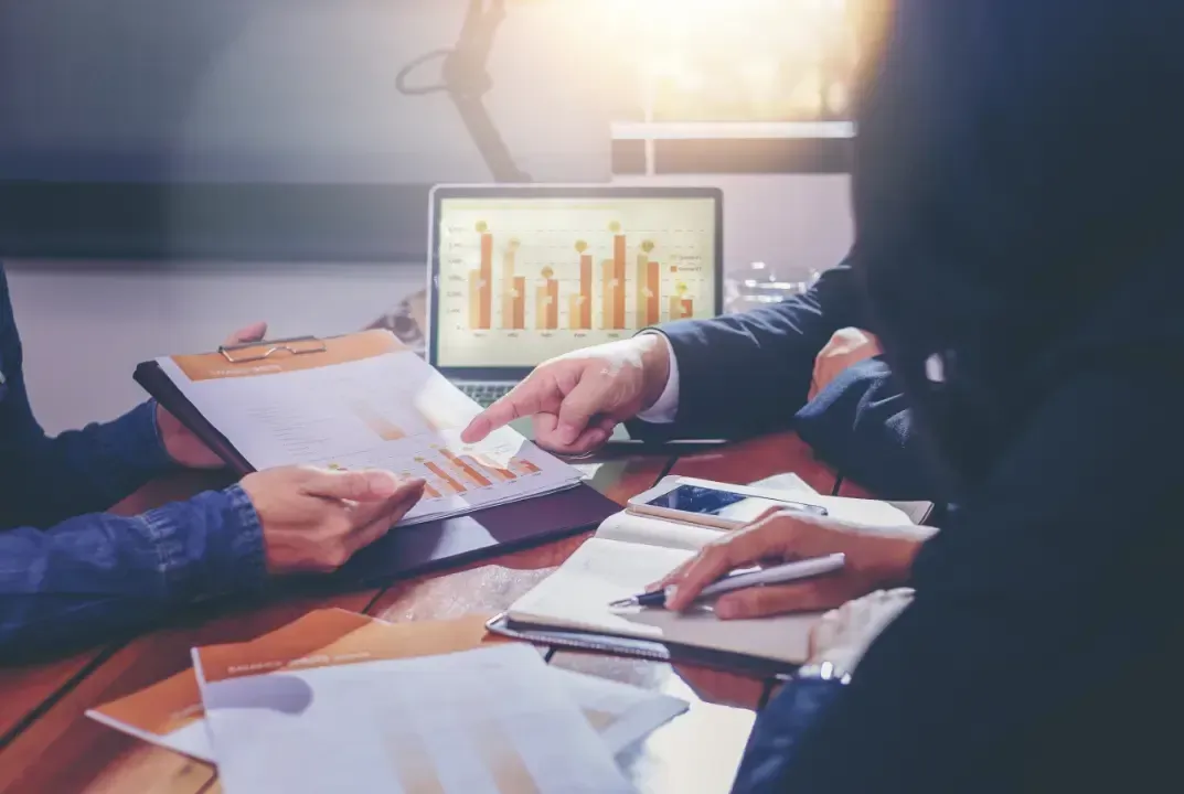 Team members sitting together, discussing strategies and pointing at a graph