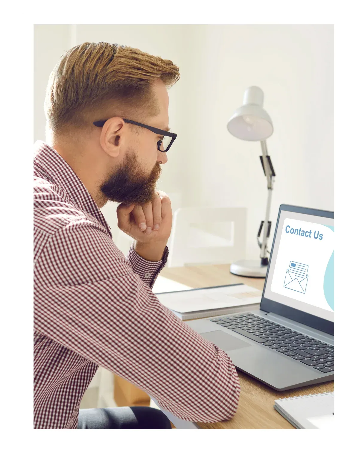 Man sitting at a desk, working on a laptop in a focused posture