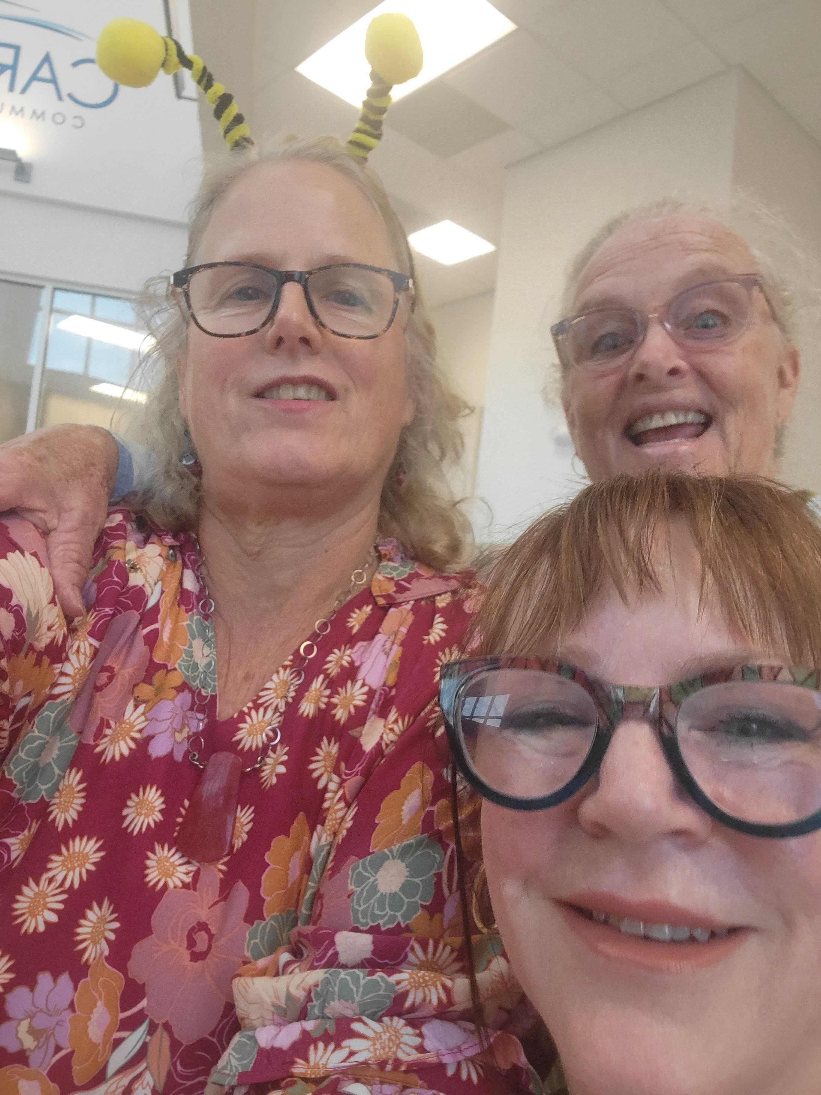 Portrait of Dr. Elena Morales, a Latina entomologist in her 40s, smiling warmly in a sunlit botanical garden, wearing a green field jacket and holding a notebook. The background features blooming wildflowers and bee boxes, emphasizing her expertise in pollinator research and community education.