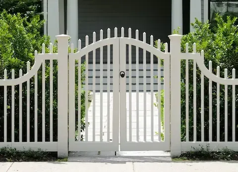 Decorative white arched picket gate at the entrance of a residential walkway